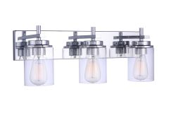 Part of the Reeves Vanity Collection, the Reeves - 17423 is a modern three-light fixture with clear glass cylinder shades and exposed bulbs on a sleek chrome rectangular base featuring metallic accents, ideal as a wall sconce to elevate any space.