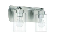 The Hendrix - 17614BNK2 is a modern wall-mounted light with two exposed bulbs in cylindrical glass shades, offering a sleek metallic finish and rectangular backplate. It exemplifies a luxurious transitional style fit for any sophisticated space.
