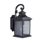 The Gentry - Z3204-MN is a classic black outdoor wall lantern with a decorative curved arm and clear beveled glass panels. It features a detailed rectangular base, making it an ideal stylish wall-mounted fixture.